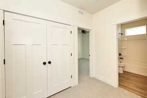 Bedroom featuring light colored carpet, baseboards, and ensuite bath