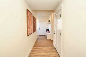 Corridor featuring light wood-style floors, recessed lighting, a textured ceiling, and baseboards