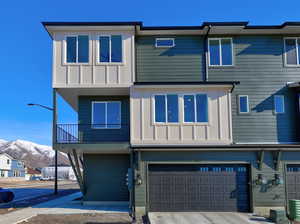 Multi unit property featuring a mountain view, a garage, board and batten siding, a balcony, and driveway