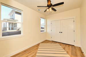 Unfurnished bedroom with baseboards, light wood-style floors, a closet, and a ceiling fan