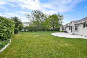 View of grassy yard featuring a patio