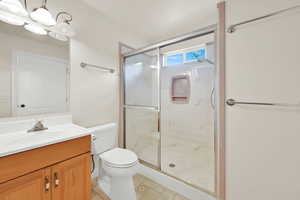 Bathroom featuring a stall shower, toilet, vanity, and a chandelier