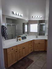 Bathroom with a shower stall, tile patterned flooring, and double vanity