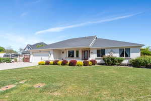 Ranch-style house featuring an attached garage, driveway, a front lawn, and stucco siding