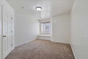 Unfurnished room with carpet floors, a textured ceiling, and baseboards