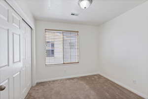 Unfurnished bedroom with carpet flooring, a closet, baseboards, and a textured ceiling