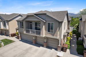 View of front of home with a garage, stucco siding, a shingled roof, and concrete driveway