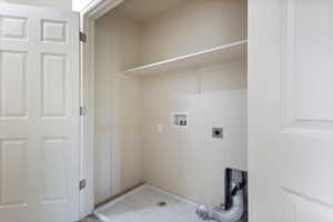 Laundry area with hookup for an electric dryer, hookup for a washing machine, and baseboards