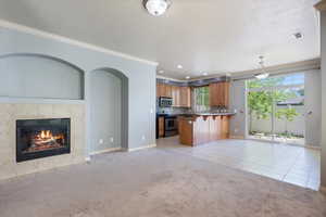 Kitchen featuring stainless steel appliances, crown molding, open floor plan, light colored carpet, and a breakfast bar