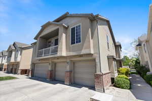 View of front of home with brick siding, an attached garage, stucco siding, and concrete driveway