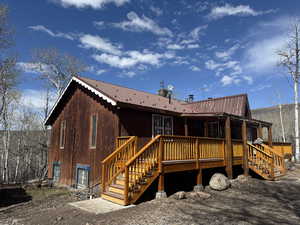 Front view of property with metal roof, a wooden deck, and stairway