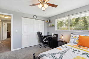 Bedroom with carpet, a closet, an office area, ceiling fan, and baseboards