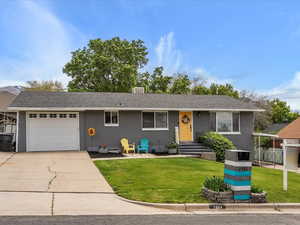 Single story home with an attached garage, driveway, and a front lawn