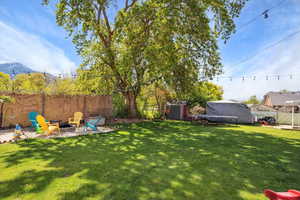 View of yard with an outdoor fire pit, a storage shed, a mountain view, and an outbuilding
