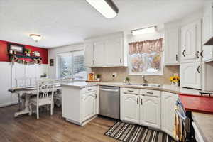 Kitchen with stainless steel appliances, a sink, a textured ceiling, wood finished floors, and white cabinets