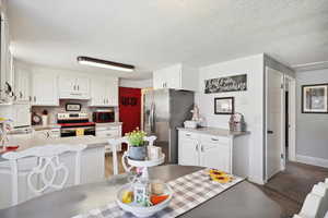 Kitchen featuring stainless steel appliances, under cabinet range hood, a peninsula, white cabinets, and light countertops