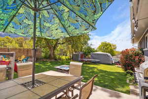 View of patio with outdoor dining area, a storage unit, an outdoor structure, and a fire pit