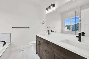 Full bath featuring double vanity, baseboards, a bath, toilet, and recessed lighting