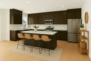 Kitchen featuring stainless steel appliances, light wood-type flooring, a kitchen breakfast bar, light countertops, and recessed lighting