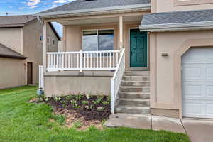 Doorway to property with a porch, roof with shingles, stucco siding, and a garage