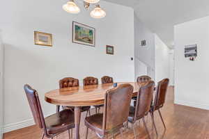Dining room featuring wood finished floors, baseboards, stairs, and lofted ceiling