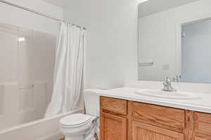 Bathroom with toilet, vanity, and shower / tub combo with curtain