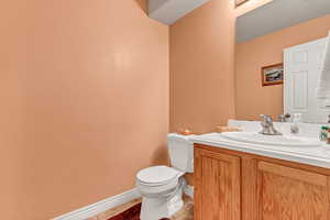 Half bath with toilet, tile patterned flooring, vanity, and baseboards