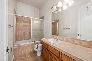 Full bath with vanity, tiled shower / bath, toilet, and tile patterned flooring