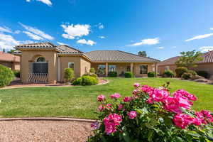 Rear view of house with a tiled roof, stucco siding, and a lawn