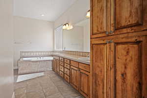 Full bathroom featuring a garden tub, tile patterned flooring, and double vanity