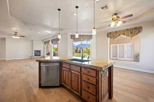Kitchen with a sink, stainless steel dishwasher, ceiling fan, brown cabinetry, and a textured ceiling
