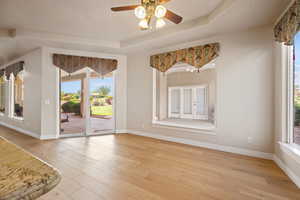 Unfurnished room featuring light wood-type flooring, ceiling fan, healthy amount of natural light, and baseboards