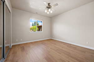 Unfurnished bedroom with baseboards, light wood-type flooring, a closet, and a ceiling fan