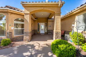 Property entrance featuring stone siding, stucco siding, and a tiled roof