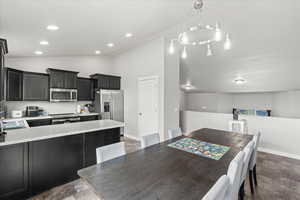 Dining room featuring baseboards, stone finish floor, vaulted ceiling, and recessed lighting