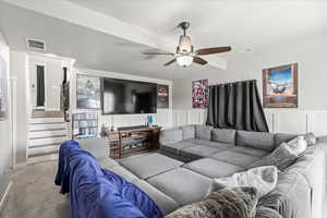 Living area with stairway, carpet, a ceiling fan, and visible vents