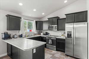 Kitchen with a peninsula, recessed lighting, light countertops, a sink, and stainless steel appliances