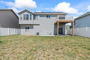 Rear view of property featuring a fenced backyard, a wooden deck, a yard, and a patio area