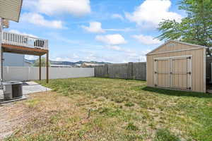 View of yard featuring a fenced backyard, a storage unit, an outdoor structure, and central AC