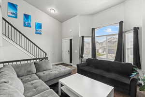 Living room featuring baseboards, a towering ceiling, wood finished floors, and stairway