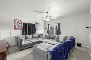 Living area featuring a ceiling fan, a textured ceiling, and light carpet