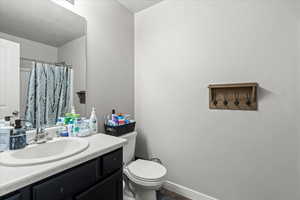Full bathroom with toilet, a shower with shower curtain, and vanity