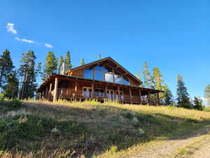 Rear view of property featuring log veneer siding, a chimney, and a wooden deck