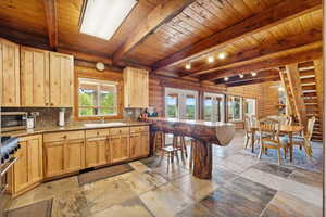 Kitchen with light brown cabinets, rustic walls, stainless steel appliances, wooden ceiling, and french doors