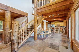 Staircase featuring wood ceiling, beam ceiling, and stone tile floors