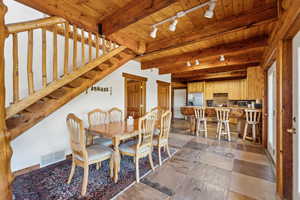 Dining area featuring rail lighting, wood ceiling, beam ceiling, and stairs