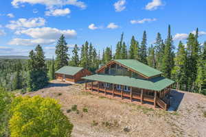 Back of property featuring a porch, a wooded view, and metal roof