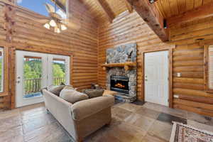 Living area featuring beamed ceiling, wood ceiling, high vaulted ceiling, a fireplace, and a ceiling fan