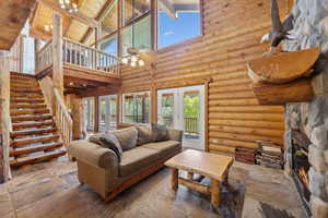 Living area featuring high vaulted ceiling, wood ceiling, stairs, beam ceiling, and a fireplace