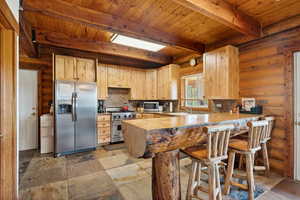Kitchen with stainless steel appliances, light brown cabinetry, beam ceiling, wooden ceiling, and a peninsula